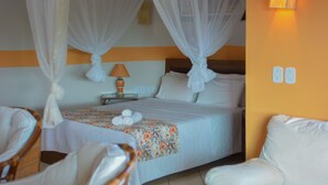 Habitación de hotel con cama, dos sillas, mesita de noche con lámpara y pared con dos interruptores de luz.