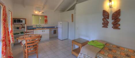 A compact living space with a dining area, kitchenette, and a sofa with a patterned throw.