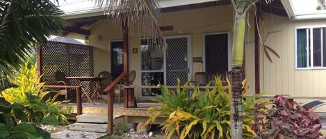 A house with a porch, outdoor seating, and tropical plants.