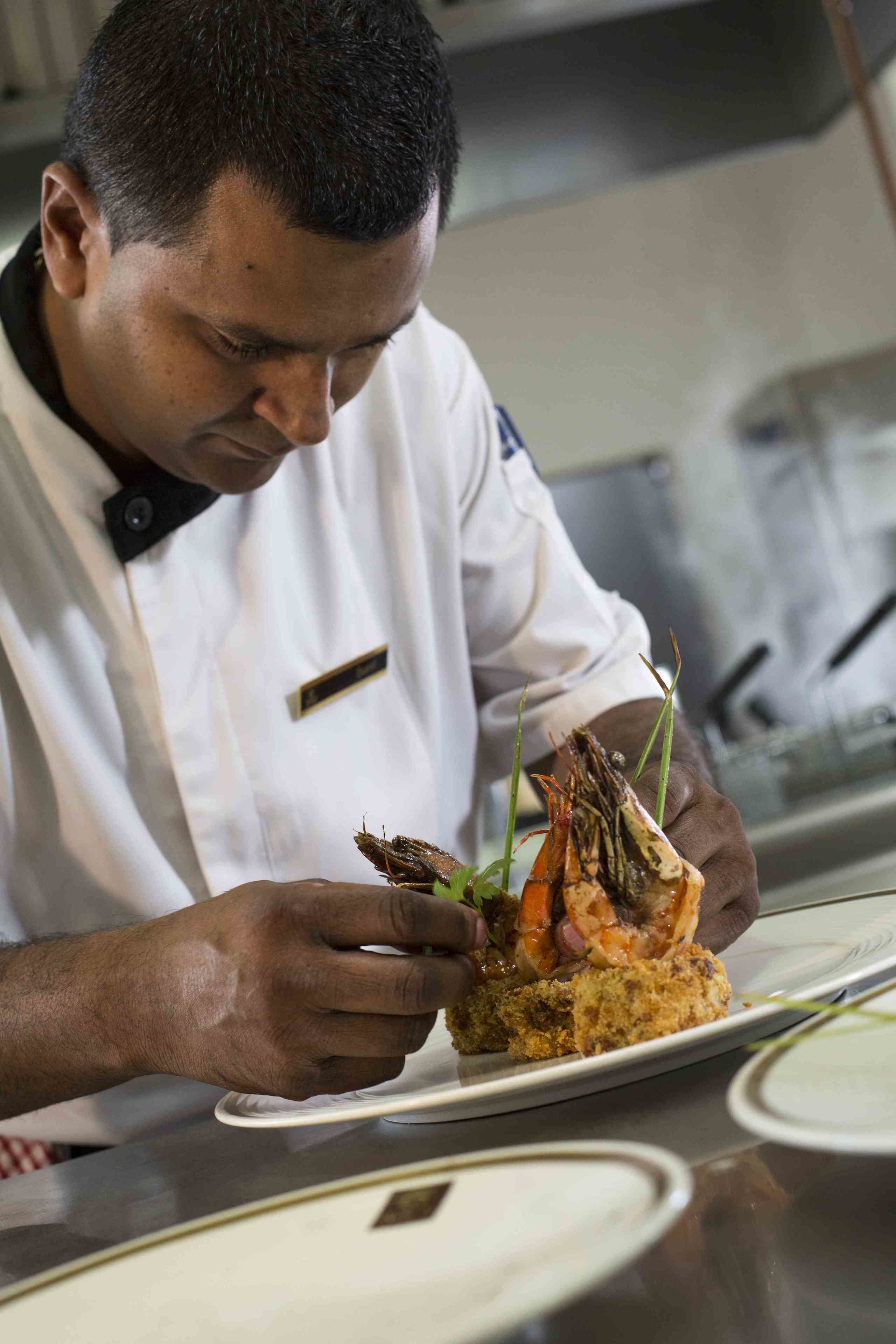 Un chef sosteniendo un plato de camarones y verduras.