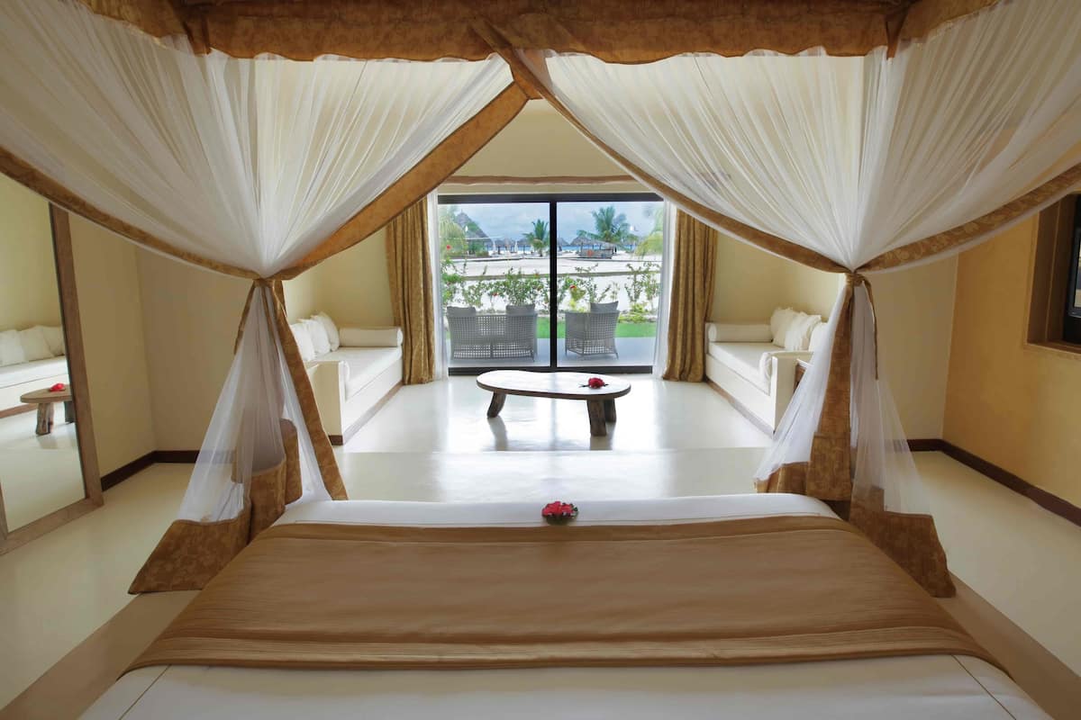 A bedroom with a large bed, a small table, and a view of the outdoors.
