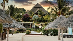 Um resort com um edifício em formato de pirâmide, palmeiras e guarda-sóis de palha.