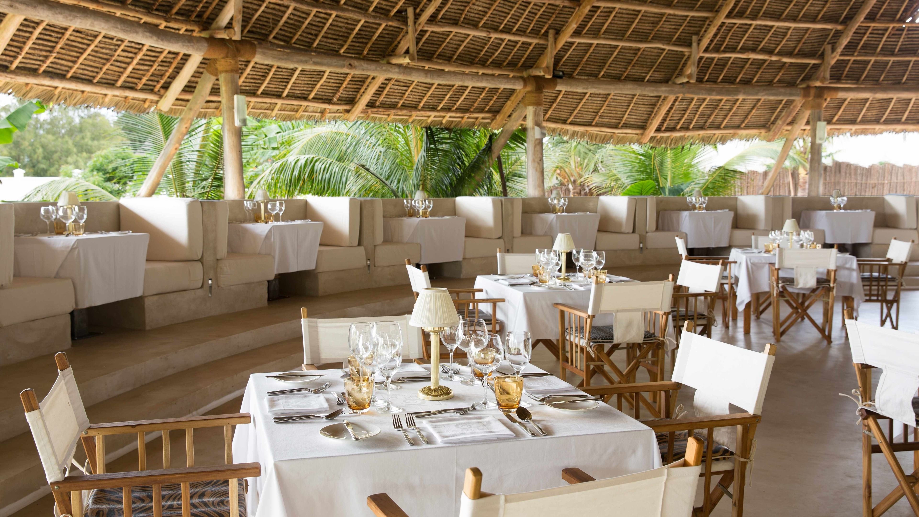 Ein Restaurant mit Außenbereich, weißen Tischdecken und Holzkästen.