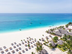 A beach resort with thatched-roof huts, palm trees, and a clear view of the ocean. - Gold Zanzibar Beach House & Spa (Kendwa)