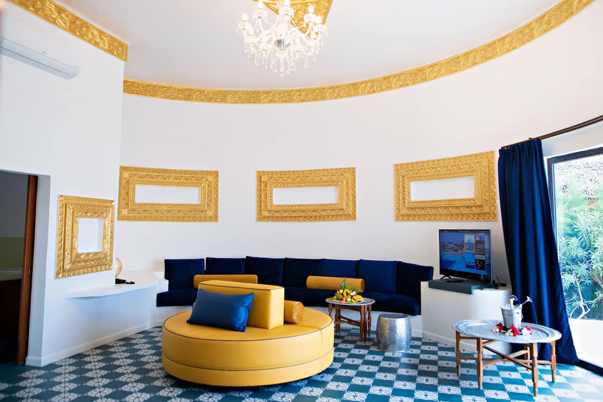 A modern living room with a yellow sofa, blue cushions, a small round table, and a television.