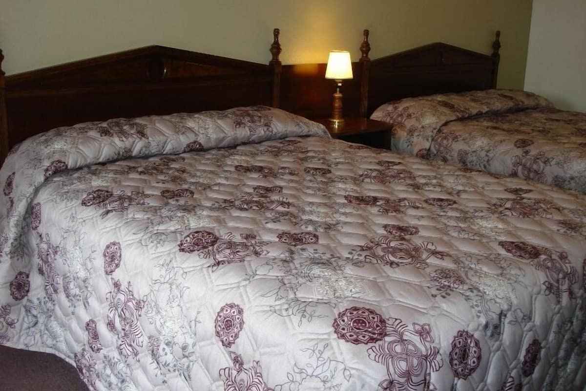 A double bed with a floral-patterned duvet and a wooden headboard.