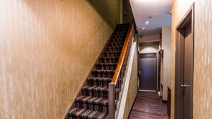 A staircase with striped carpet and wooden handrails leading to a door marked with the number 2.