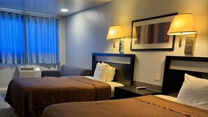 A hotel room with two beds, a desk, a chair, a lamp, and a window with curtains. - Country Manor Motel Watkins (Watkins)