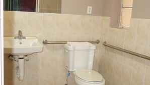 A bathroom with a toilet, sink, and grab bars. - Palm City Motel (Fort Myers)
