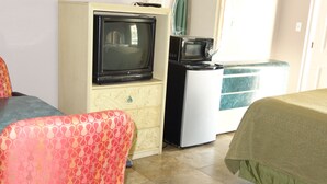 A hotel room with a bed, a desk with a television, a refrigerator, and a chair. - Palm City Motel (Fort Myers)