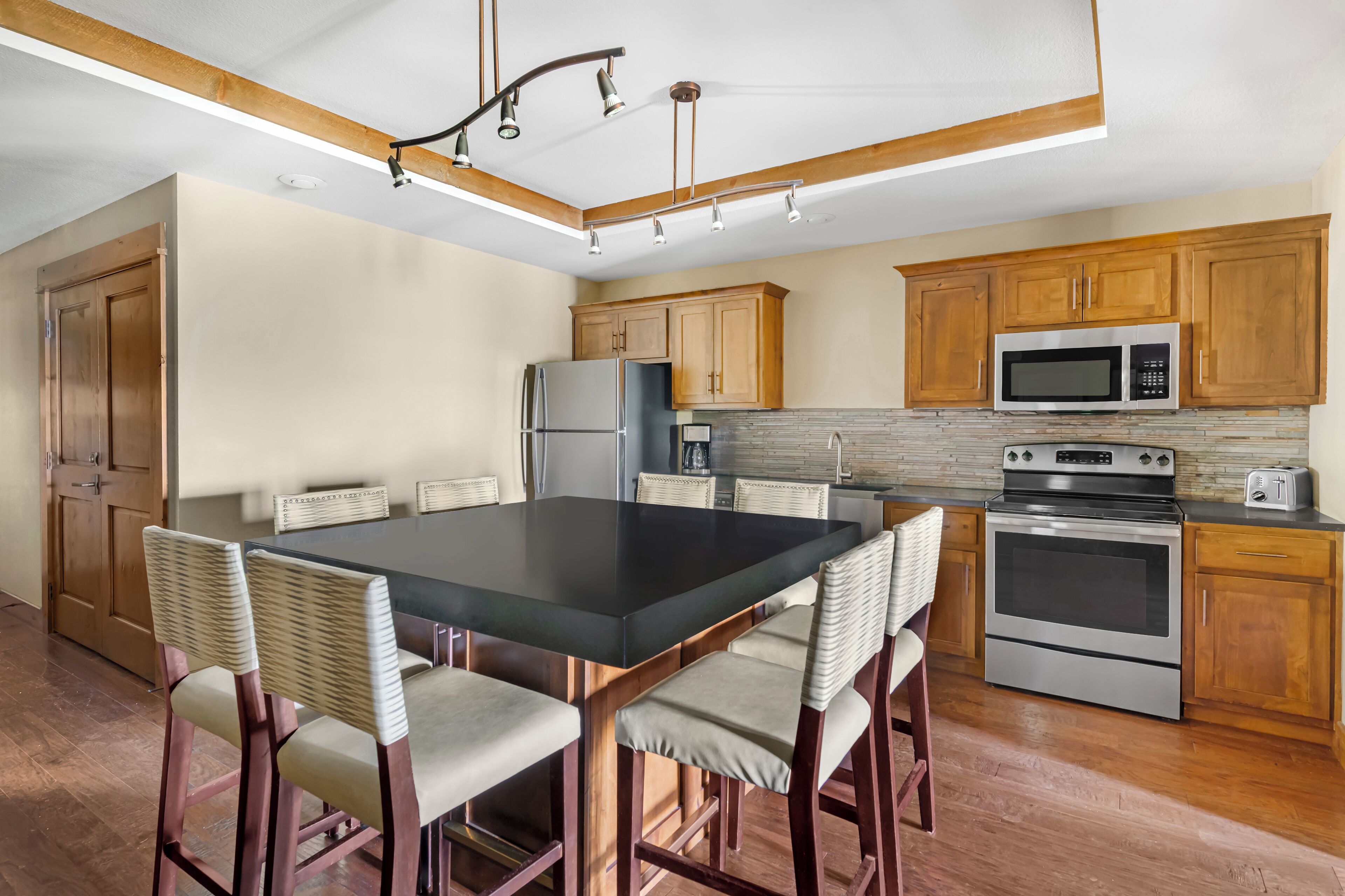 A modern kitchen with a large island, stainless steel appliances, and wooden cabinetry.