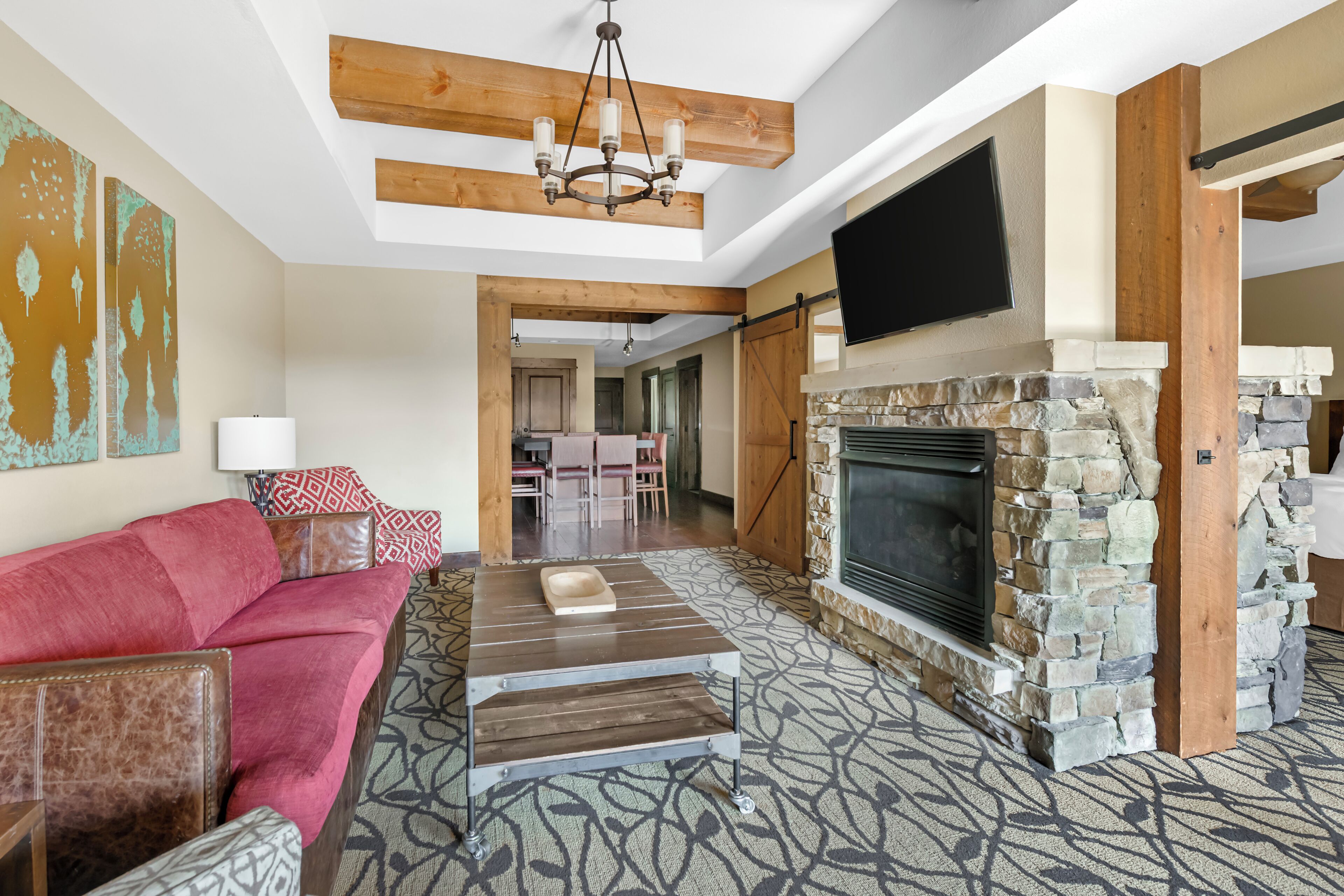 A spacious living room with a fireplace, a red sofa, and a patterned carpet.