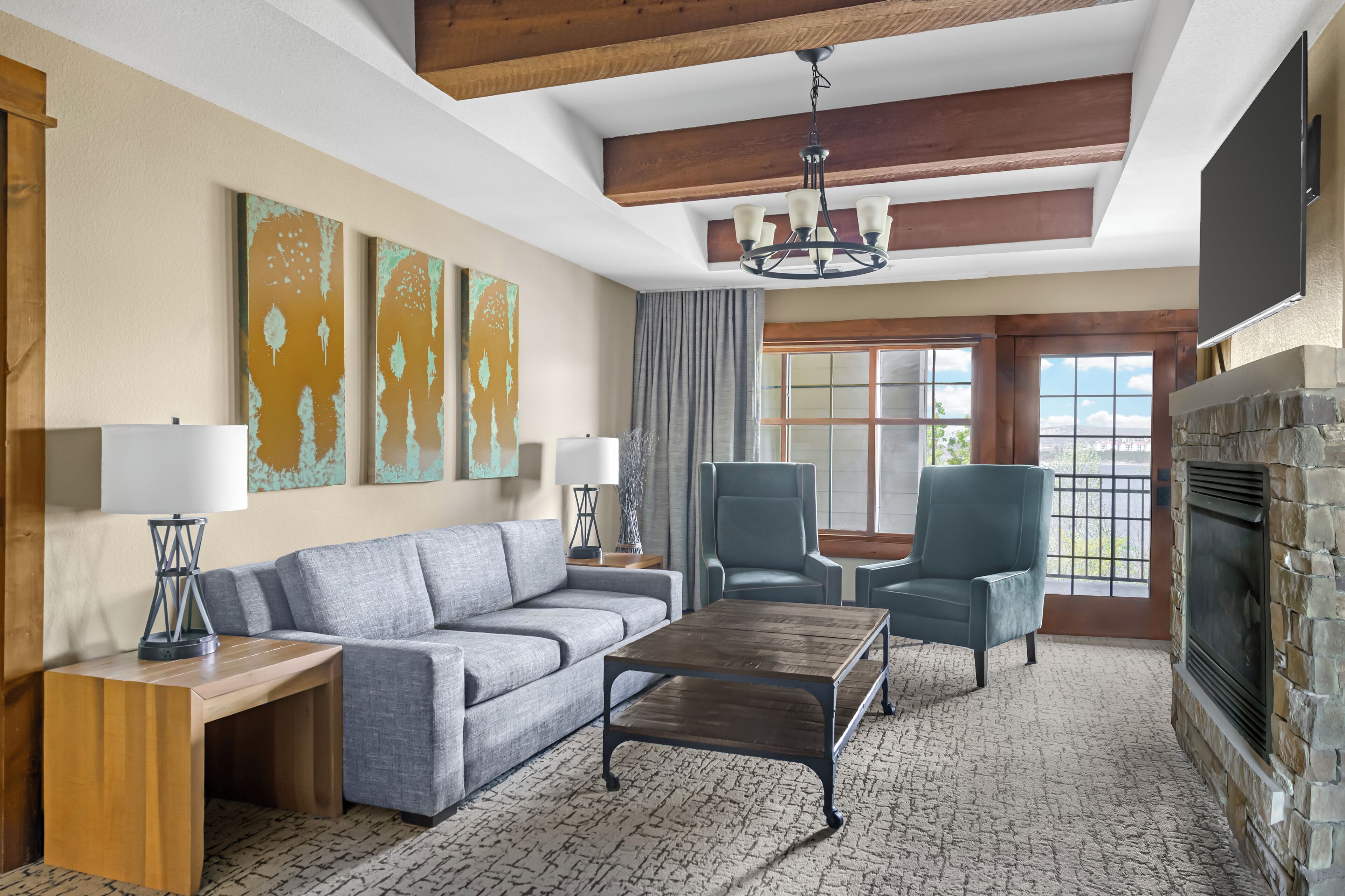 A living room with a sofa, two armchairs, a coffee table, a fireplace, and artwork on the walls.
