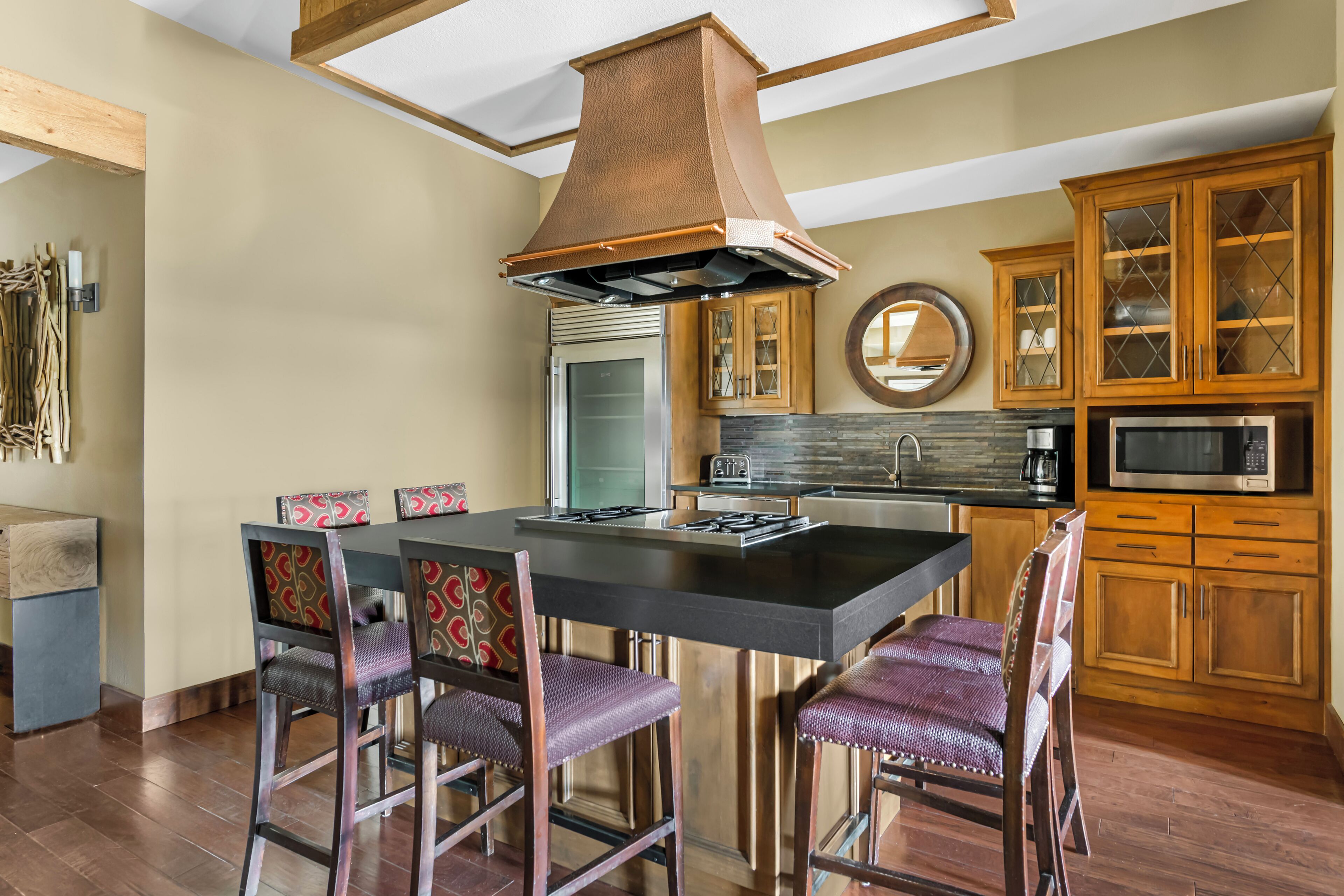 A modern kitchen with a central island, wooden cabinets, and a built-in microwave.