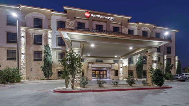 Un hotel con una facciata moderna, un ingresso evidente e un giardino anteriore curato.