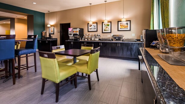 Un restaurant moderne doté d’un bar, de tables et de chaises, d’un comptoir avec une machine à café et de tableaux encadrés aux murs.