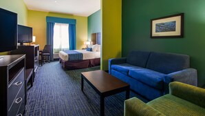 Une chambre d’hôtel avec un lit, un canapé, une télévision, un bureau et une chaise.
