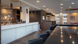 Un área de bar moderna con una barra larga, diversas opciones de asientos y una variedad de utensilios y botellas.