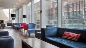 Un moderno hall de hotel con una amplia zona de estar, ventanas grandes y vistas a la ciudad.