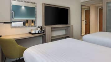 Habitación de hotel con cama, escritorio, silla, televisor de pantalla plana y espejo.
