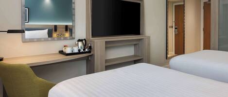 A hotel room with a bed, a desk with a chair, a flat-screen TV, and a mirror.