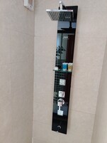 A modern bathroom with a vertical glass panel, a showerhead, and a control panel with buttons.
