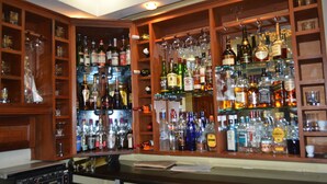 Zona de bar con estantes llenos de botellas de licores y vasos.