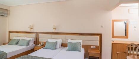 A hotel room with three beds, a desk, a chair, and a mirror.