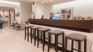 Zona de bar con mostrador, taburetes y una variedad de botellas.