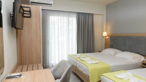 Habitación de hotel con dos camas, un escritorio, una silla, televisor montado en la pared y un equipo de aire acondicionado.