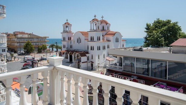 Un edificio blanco con múltiples cúpulas y un balcón con vistas a la costa.
