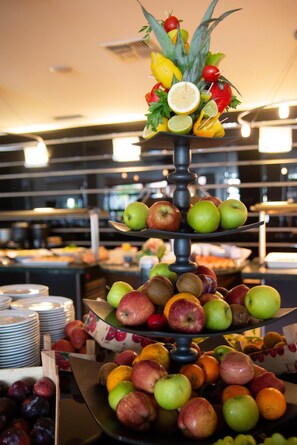 A fruit display with multiple tiers of apples, oranges, and other fruits.
