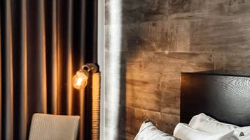 A modern hotel room with a large bed, a chair, and a wooden accent wall.
