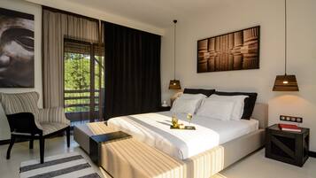 Een moderne slaapkamer met een groot bed, een stoel, een nachtkastje en uitzicht op groen.