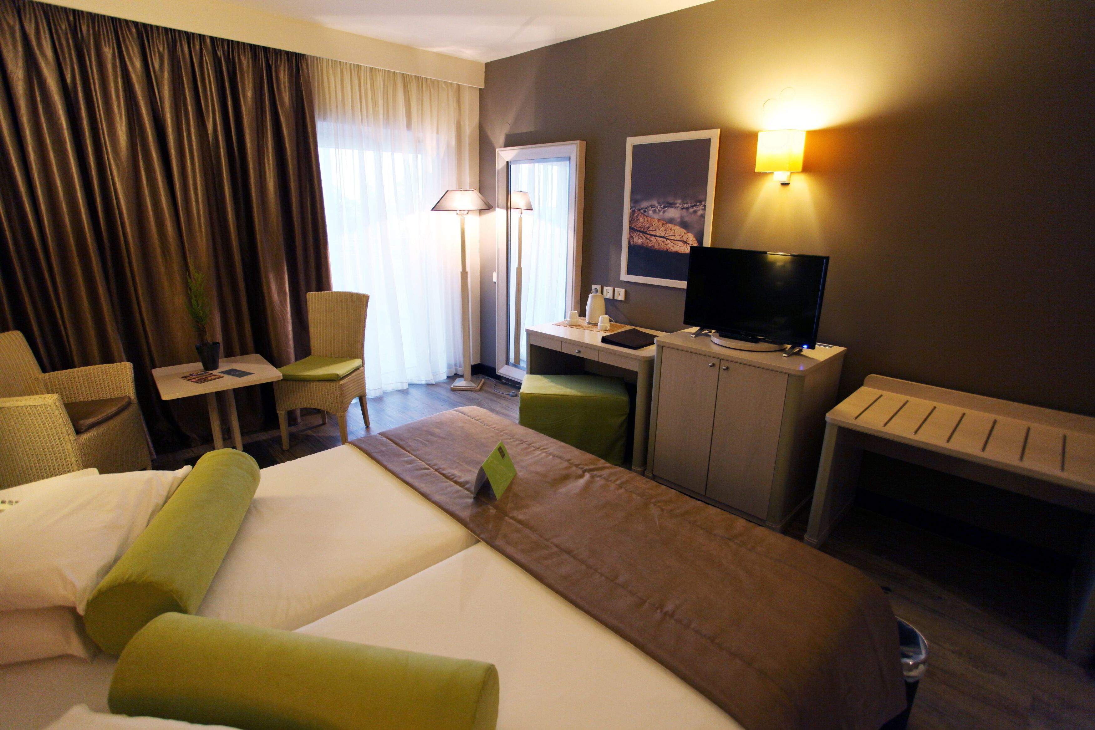Una habitación de hotel con una cama, un escritorio, una silla, un televisor y una chimenea.