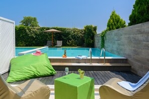 A poolside area with lounge chairs, a table with drinks, and a small hot tub.