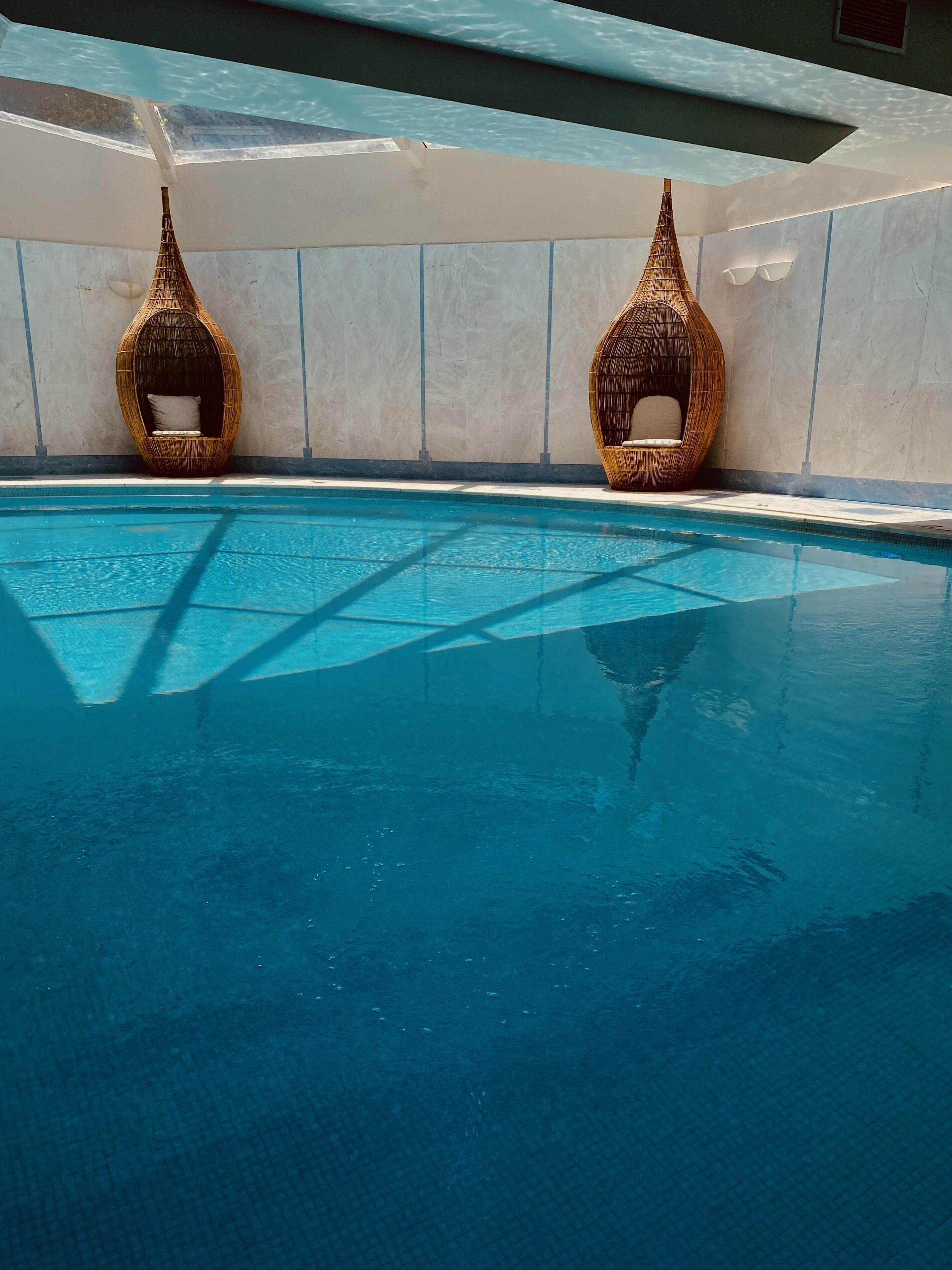 Una piscina con due sedie in vimini.