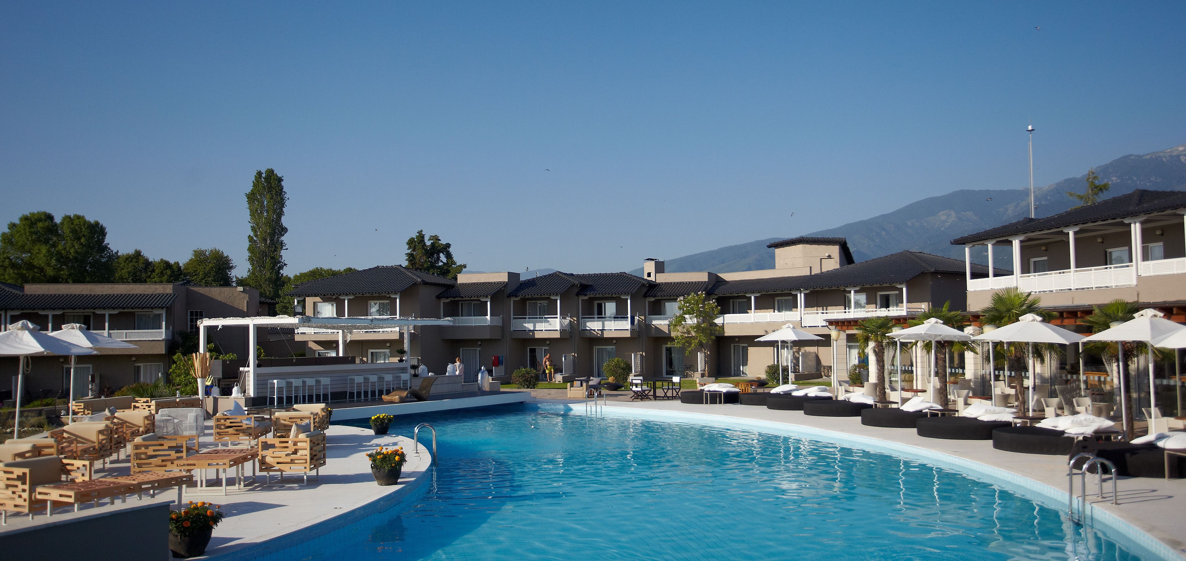 Un hotel con piscina, mobiliario exterior y vistas a la montaña.