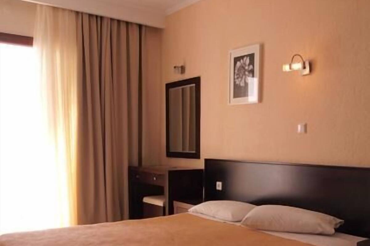 A hotel room with a large bed, a nightstand, a dresser, a mirror, and a framed picture on the wall.
