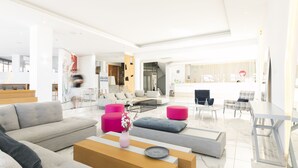 Una sala de estar moderna con un sofá, otomanas, una mesa de centro y un comedor con sillas y una mesa.