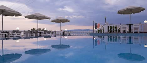 Una piscina al aire libre, sombrillas, sillones reclinables de piscina