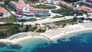 Vista aérea de un complejo turístico costero con varios edificios de hotel, una playa y una zona de piscina.