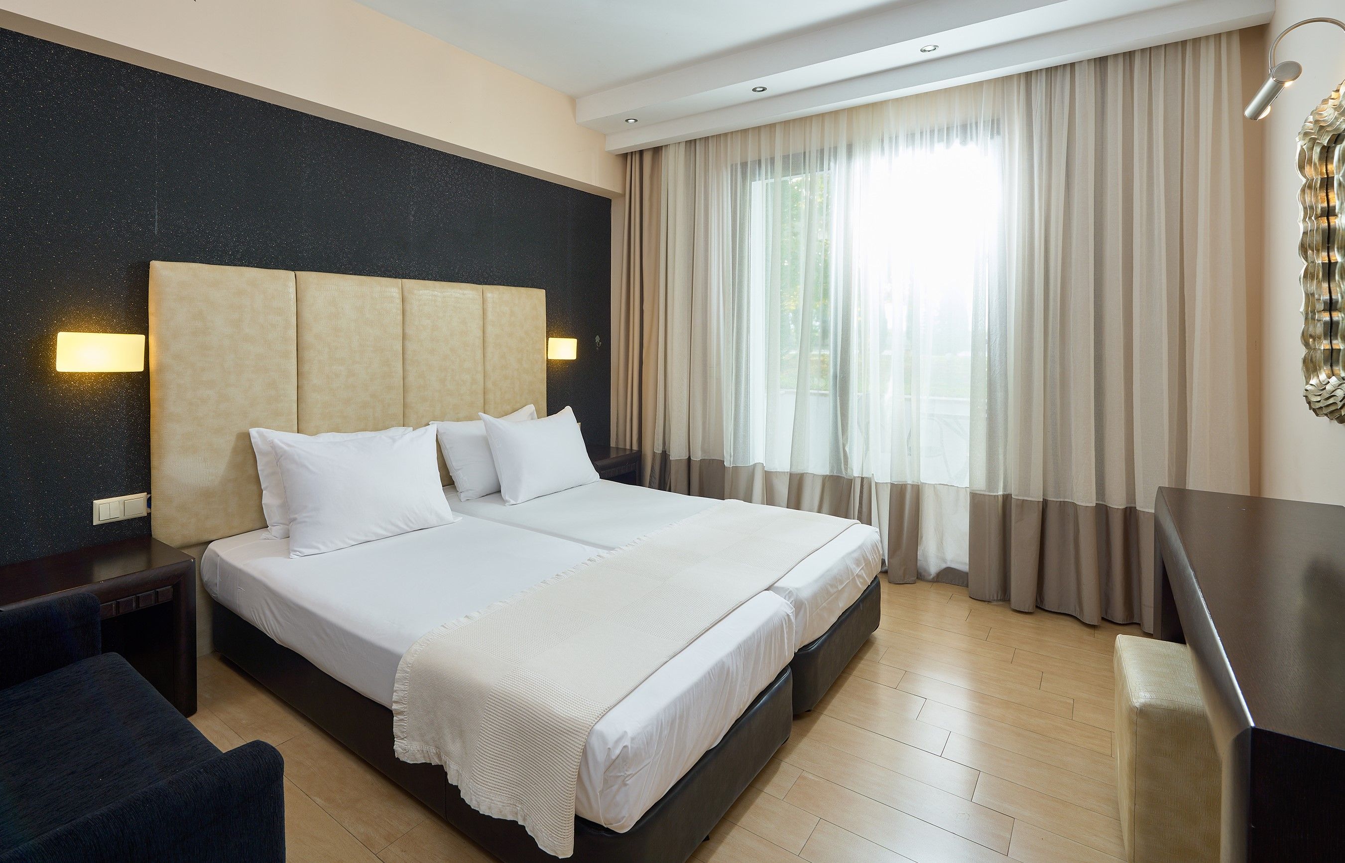 A hotel room with a large bed, a desk, and a chair.