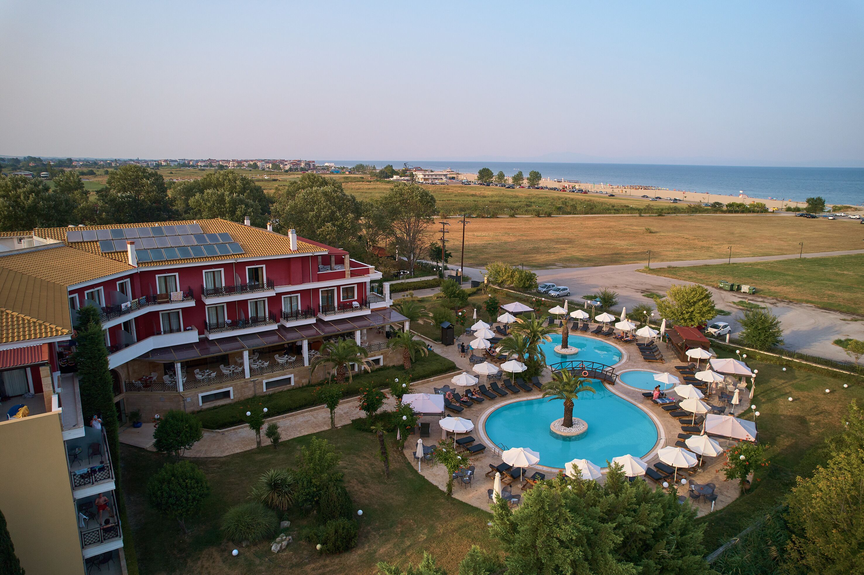Un hotel con varias piscinas, mobiliario exterior y vistas a la playa.