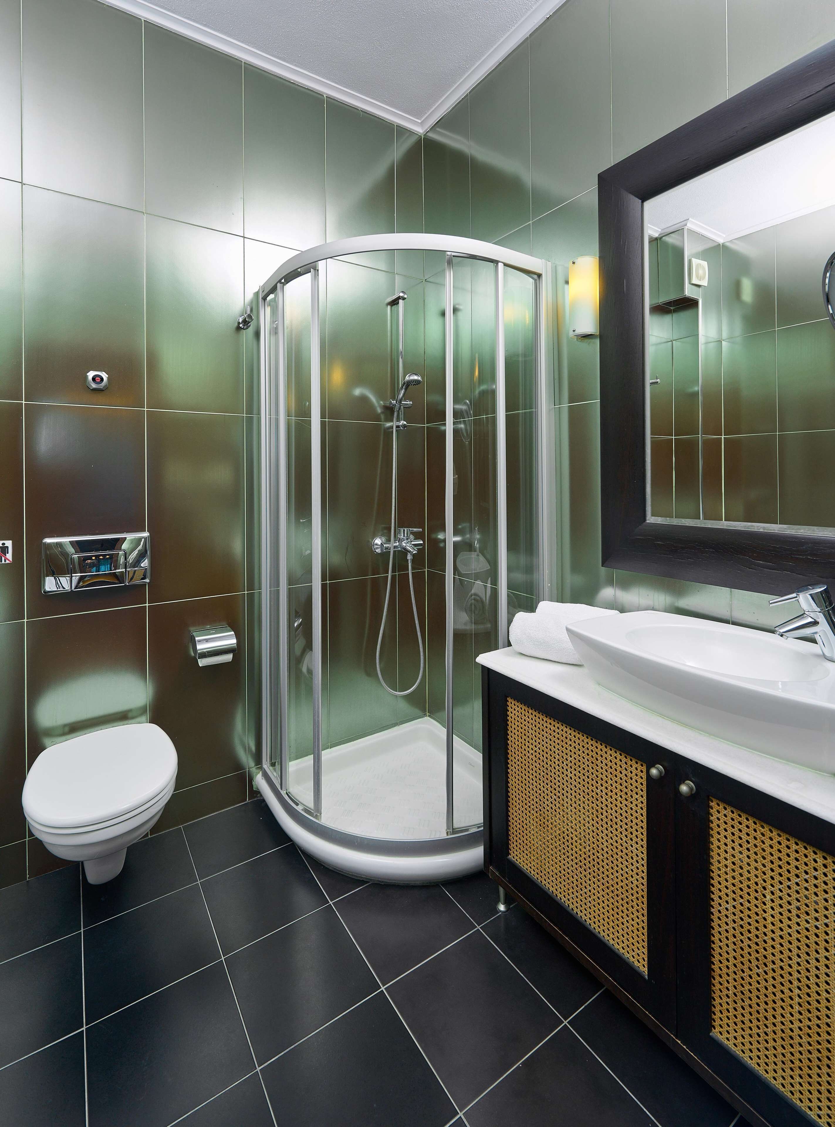 A modern bathroom with a glass-enclosed shower, a white toilet, and a vanity with a sink and mirror.