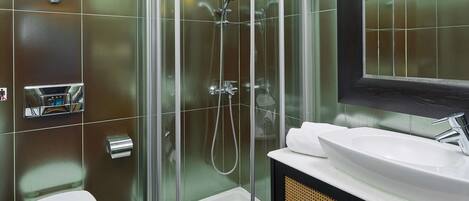 Un baño moderno con ducha de vidrio, inodoro blanco y tocador con lavabo y espejo.