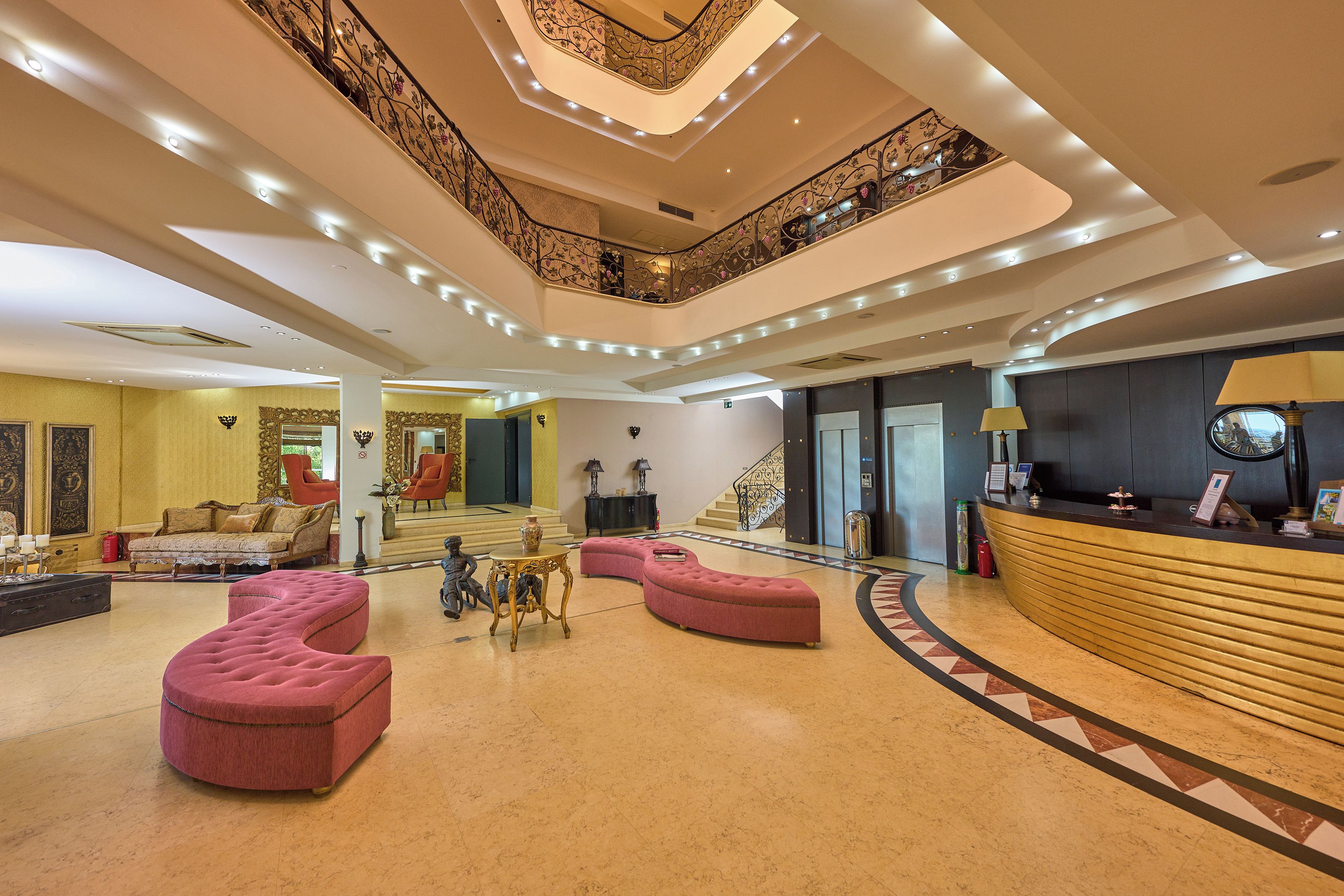 A spacious lobby with a reception desk, seating areas, and a staircase leading to an upper level.