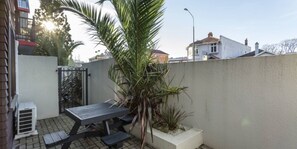A patio area with a wooden table and benches, surrounded by a low wall and potted plants. - 755 Regal Court (Dunedin)