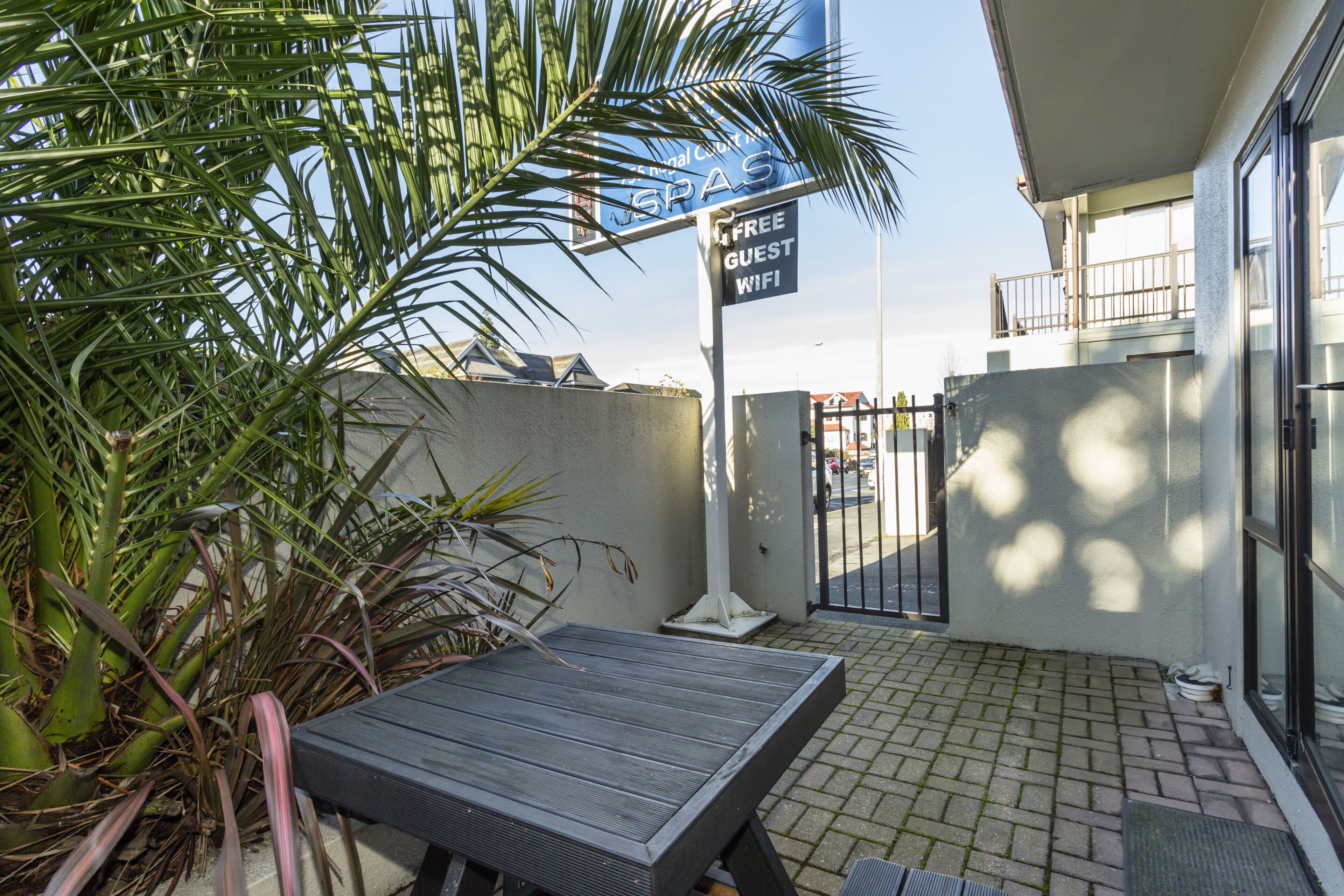 A patio area with a table, a sign offering free guest WiFi, and a gate.