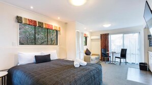 A hotel room with a large bed, a desk, a chair, and a TV. - 755 Regal Court (Dunedin)